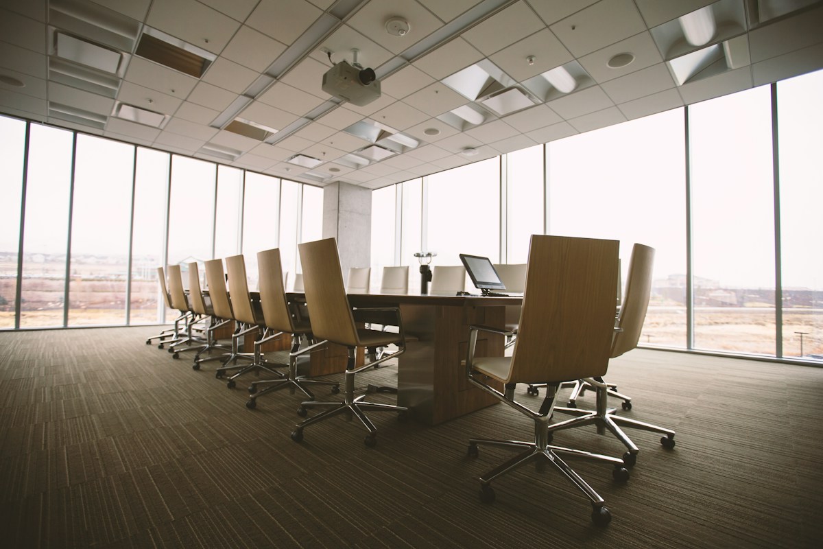 Boardroom with a long conference table and high-backed chairs beside panoramic windows