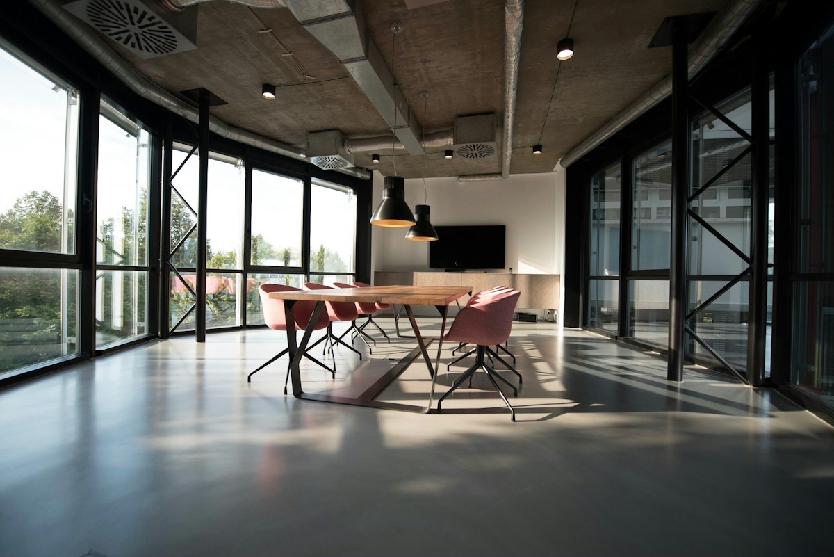 Light-filled modern meeting space with a timber table, glass walls and floor-to-ceiling windows